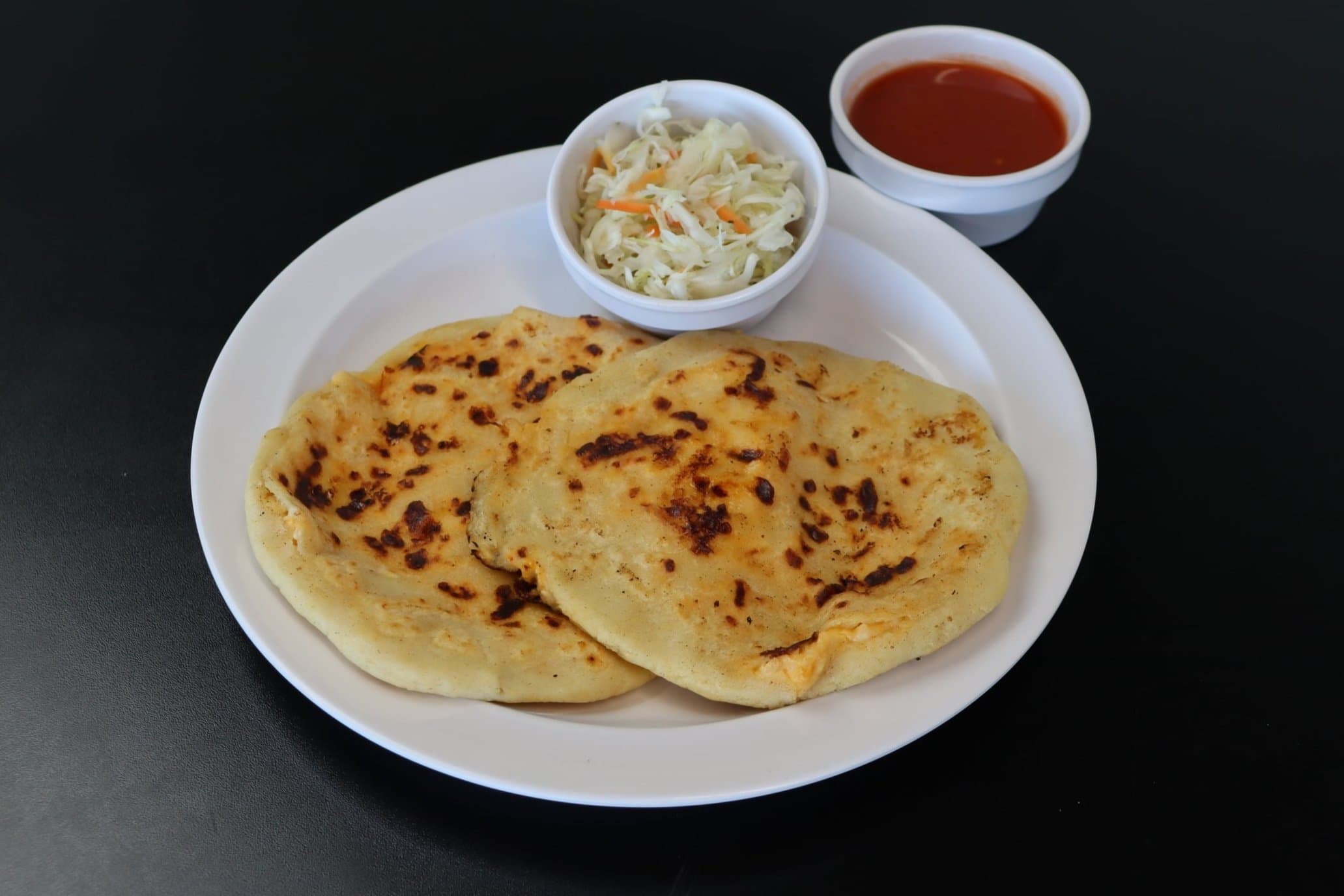 A plate of La Estrella pupusas, curtido and salsa